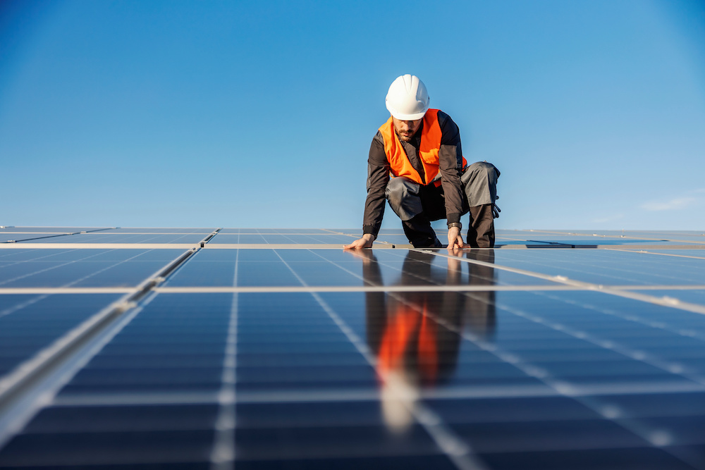 A worker installing solar panels on the roof.